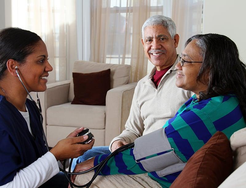 Care provider visiting with an older couple at home